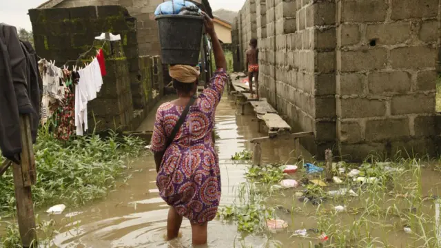 One woman wey dey walk through flooded back streets for Lagos suburb