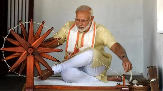 मोदी चरखा चलाते हुए