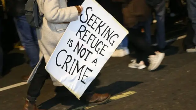 لافتة مكتوب عليها "طلب اللجوء ليس جريمة".