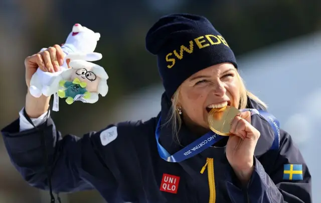 Шведская лыжница Фрида Карлссон в шутку «пробует на зуб» свою вторую золотую олимпийскую медаль