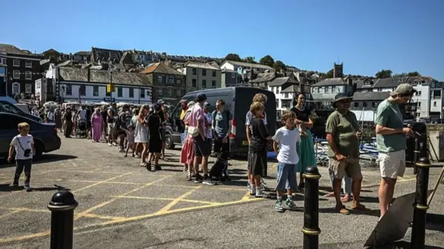 Pessoas fazem fila em Falmouth, na Inglaterra, para comprar óculos de proteção para observar o eclipse solar