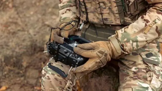 Військовий тримає в руках пульт управління дроном