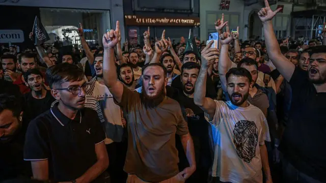 Yayımlanan bir karikatür nedeniyle Leman dergisini protesto eden bir grup İslamcı genç slogan atıyor. Arkada Tevhid bayrağı gözüküyor.