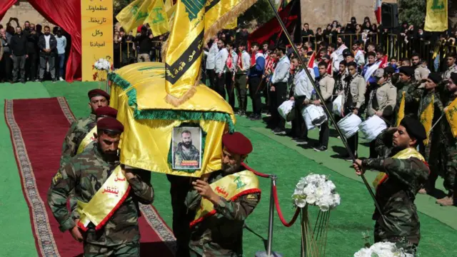 Combatentes do Hezbollah carregando o caixão de Hussein Amhaz diante de uma multidão um dia após sua morte, em 18 de setembro.
