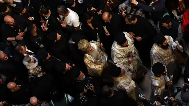 Desetine ljudi oko pravoslavnog patrijarha Jerusalima Teofila Trećeg tokom ceremonije „Svetog ognja“ u Crkvi Svetog groba, u Jerusalimu