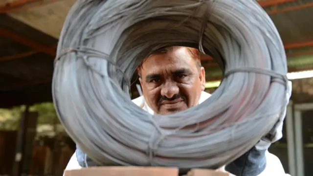 Nijazahmed Šaik viri kroz namotane žice napravljene od otpadnih čeličnih traka u njegovoj fabrici u Indiji