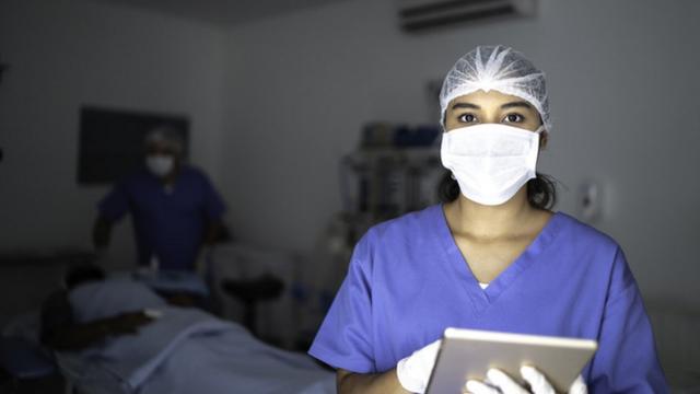 Enfermeira de máscara em quarto de hospital