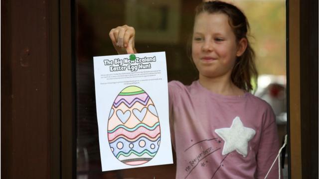 Menina coloca desenho de ovo de páscoa na janela