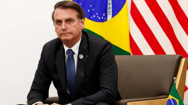 Bolsonaro sentadosporting bet aplicativosala, com bandeiras dos EUA e Brasil atrás