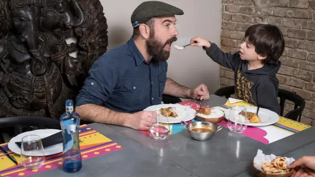 Filho dando comida para pai durante refeição