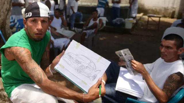 Reclusos muestran unos dibujos en la cárcel Apanteos, El Salvador.