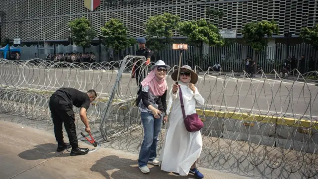 Dua warga melakukan swafoto saat personel korps Brimob memasang kawat berduri di kawasan Kantor Bawaslu, Jakarta, Selasa (21/5/2019).