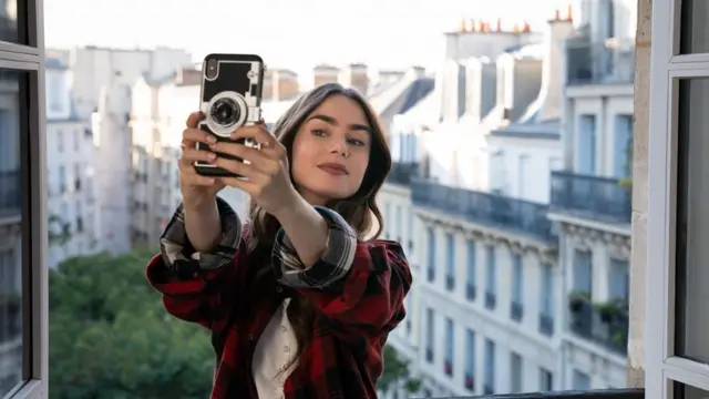 Lily Collins, interpretando Emily, tira selfieesquema de apostas esportivassacadaesquema de apostas esportivasParis, com prédios históricos ao fundo