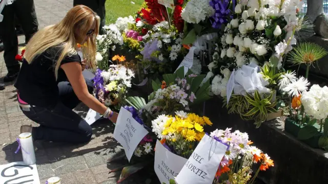 Mujer coloca flores en homenaje a los fallecidos en el naufragio