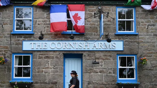 A British police officer walks past The Cornish Arms gastropub in St Ives, Cornwall on June 10, 2021,