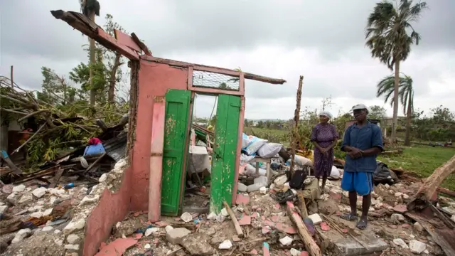 Residents next to their destroyed home