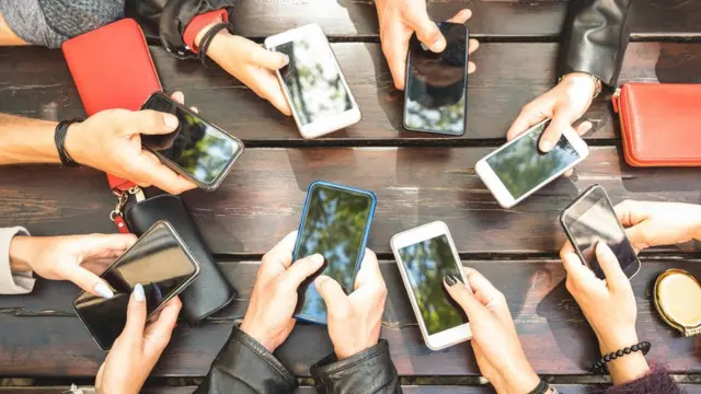 Varias personas agarrando sus móviles.