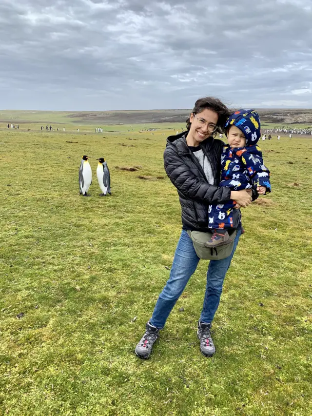Yliana Rodríguez junto a su hijo con pingüinos de fondo en las islas Malvinas / Falklands