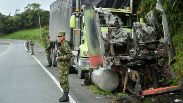 Soldados pertoroleta explicaçãocaminhão queimado parado no acostamentoroleta explicaçãouma estrada