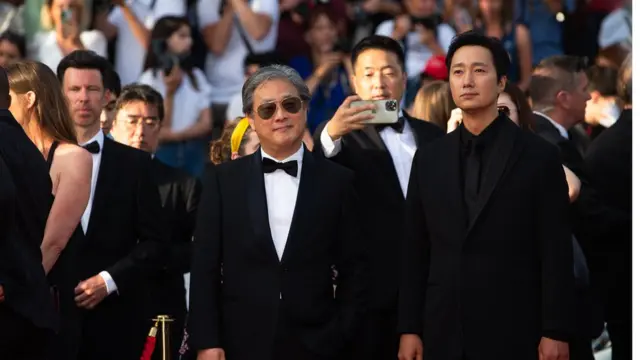 박찬욱 감독과 배우 박해일이 제75회 칸 국제영화제 폐막식에 참석해 레드카펫 위를 지나며 취재진을 향해 인사하고 있다