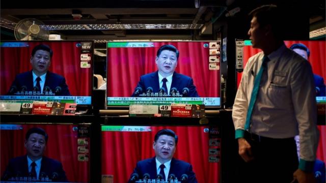 Image shows television sets showing a news report on China President Xi Jinping's speech