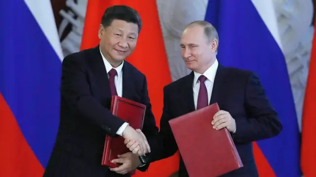 Vladimir Putin y Xi Jinping dándose la mano.