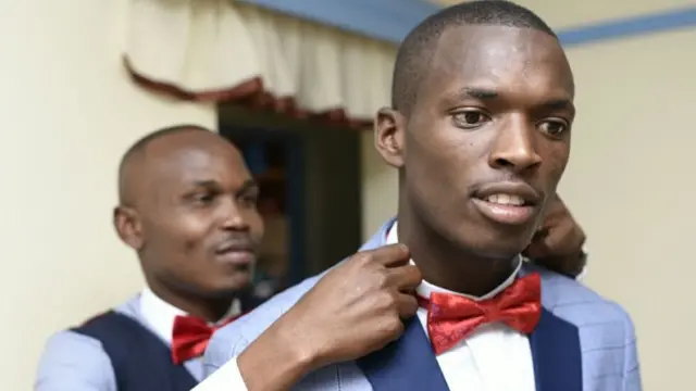 Bw Wilson akisaidiwa kuweka sawa koti lake