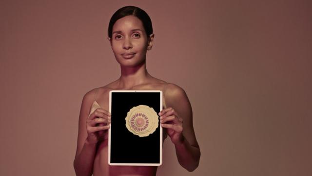 Mulher segurando um tablet na frente do corpo exibindo ilustração da estrutura interna da mama feminina