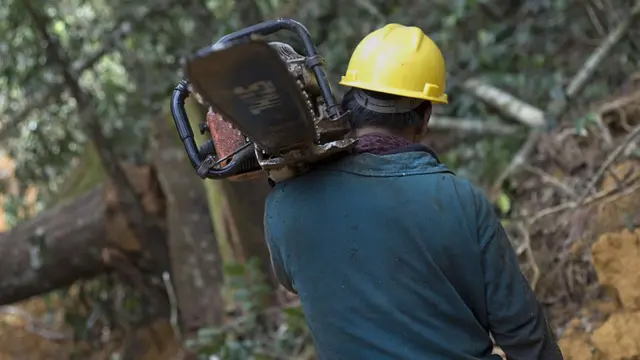 Homem carregando serrra elétrica na Indonésia