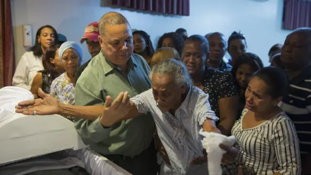 Familia y amigos de los periodistas asesinados lamentan sus muertes frente a un ataúd.
