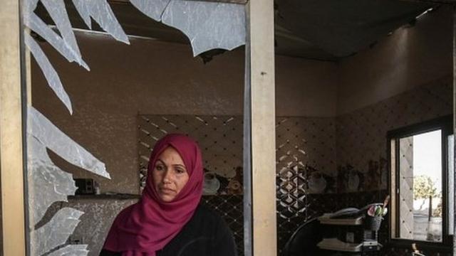 فلسطينية تنظر من خلال نافذتها المهشمة في خان يونس