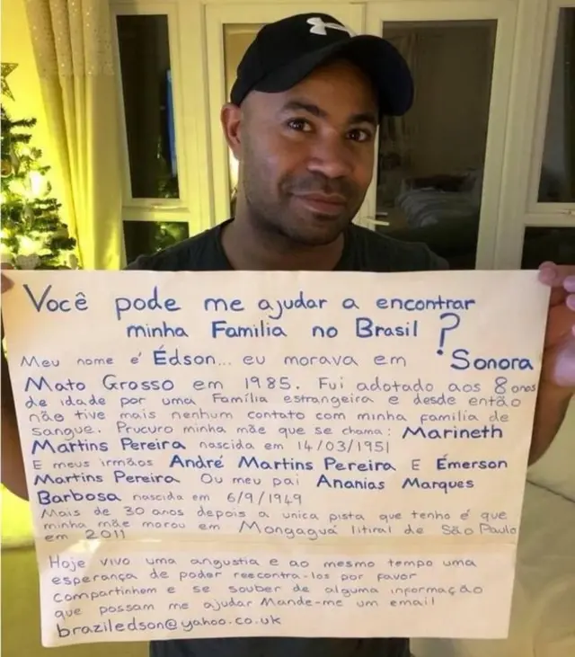 Edson segurando cartaz com informações sobre seus pais ebestes online casino echtgeldadoção