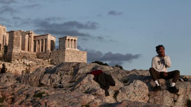 Un hombre en una colina frente a la Acrópolis de Atenas.
