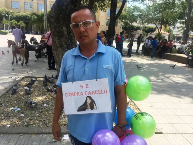 Un hombre con un aviso que dice "Se compra cabello"