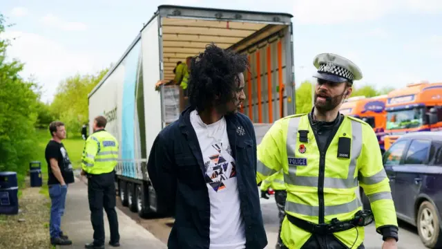 লরির পেছন থেকে এক অভিবাসনকামীকে আটক করছে ব্রিটিশ পুলিশ।