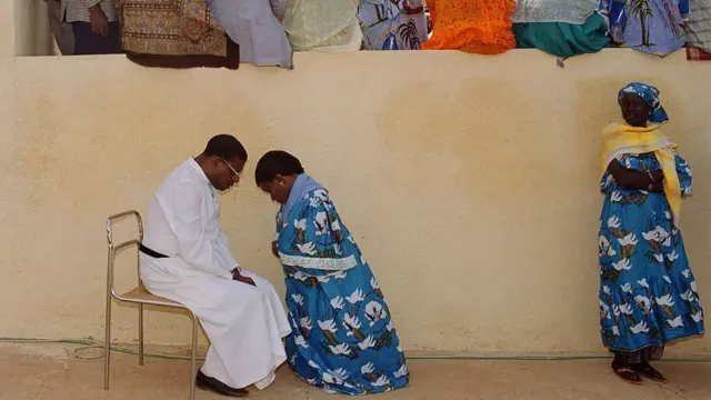 Une sénégalaise s'agenouille pour se confesser.