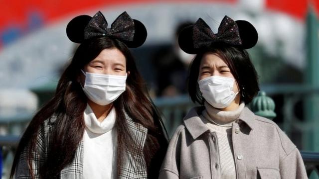 Visitors wearing protective face masks and Mickey Mouse costumes, following an outbreak of the coronavirus,