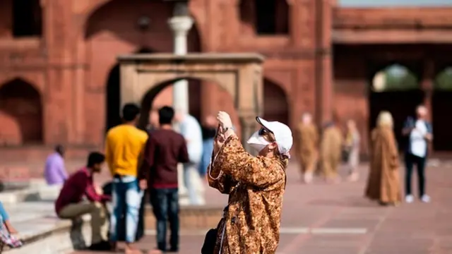 A tourist, wearing a facemask amid concerns over the spread of the COVID-19 novel coronavirus, visits the Jama Masjid mosque in the old quarters of New Delhi
