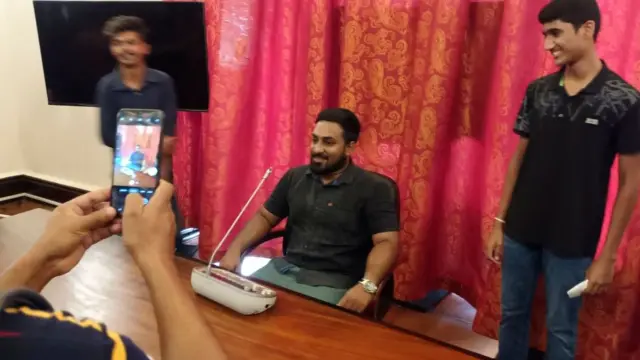 কলম্বোতে গণবিক্ষোভে প্রেসিডেন্টের প্রাসাদ তছনছ হওয়ার পর মি. রাজাপাকশার চেয়ারে বসে ছবি তুলছেন একজন অজ্ঞাতনামা বিক্ষোভকারী।