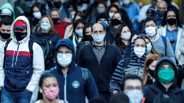 Pessoas andam na ruavulkan bet pagaSão Paulo usando máscaras