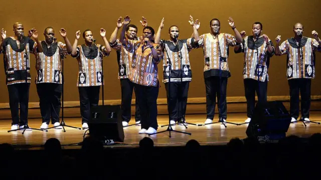 Joseph Shabalala(with mike for hand) and di rest of di South African singing group Ladysmith Black Mambazo dey perform before crowd