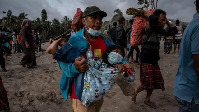 man carrying child away from volcano