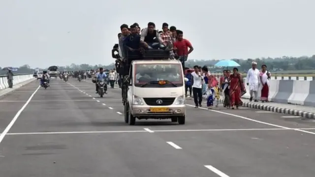 पुल से गुजरती गाड़ी और पैदल चलते लोग