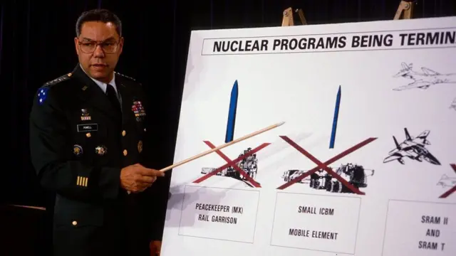 Colin Powell talks on a field phone during a visit to US forces in Saudi Arabia