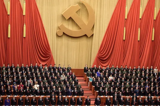 Asistentes al congreso bajo una enorme hoz y martillo