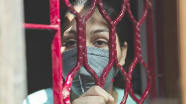 Joven detrás de una reja