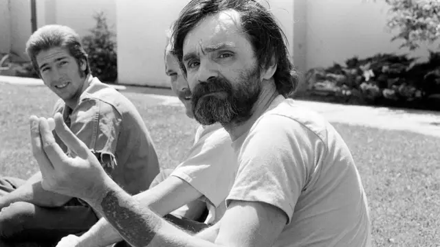 Charles Manson al aire libre con otros dos hombres
