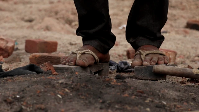 लकड़ी की चप्पलें पहनकर काम करते मजदूर