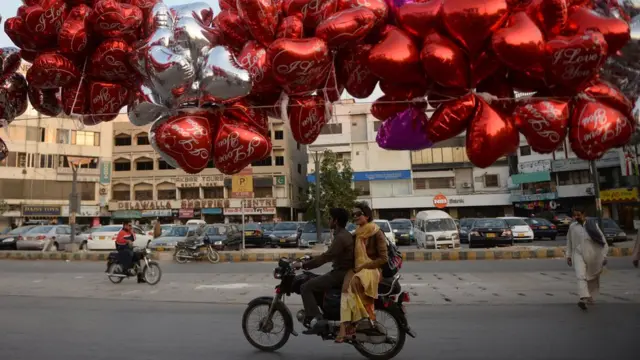 Pakistani commuters ride past balloons hanging above a Valentine's stall in Karachi on February 14, 2014. At least three students were wounded in a clash at a university in the northwestern Pakistani city of Peshawar, following a dispute over Valentine's Day celebrations in the deeply Muslim country