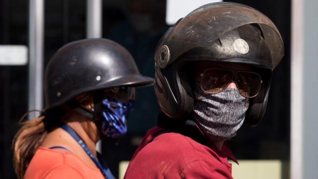 Una pareja con mascarillas de tela y cascos en Caracas, Venezuela